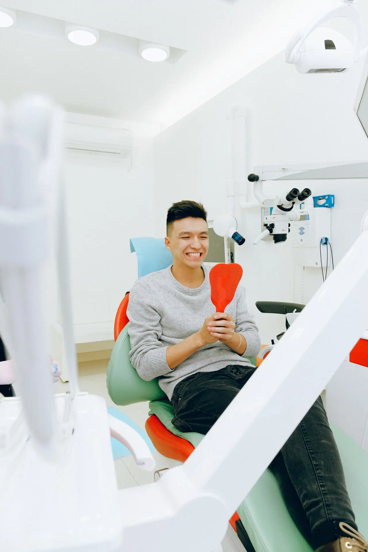 asian man smiling nad watching his own teeth in the mirror